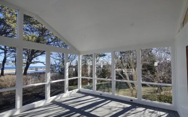 A bright white screened porch looking out toward the water
