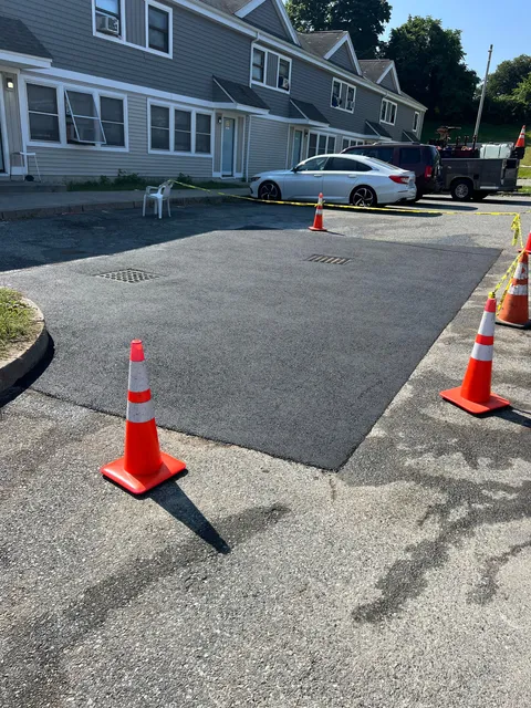 A row of orange and white traffic cones are sitting on the side of a road.