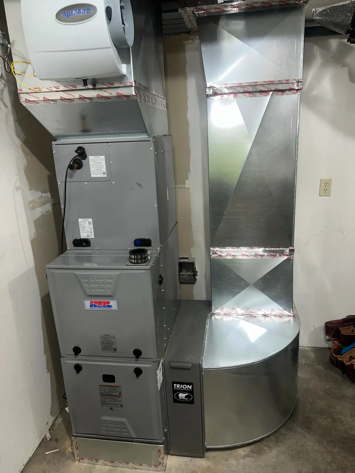 An HVAC system with a Trion indoor air quality filter, metal ductwork, and a heating/cooling unit in a basement or utility room.
