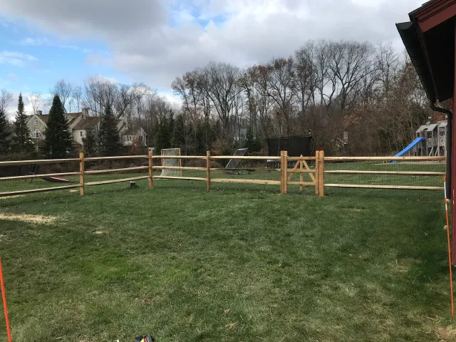 There is a wooden fence in the middle of a grassy field.