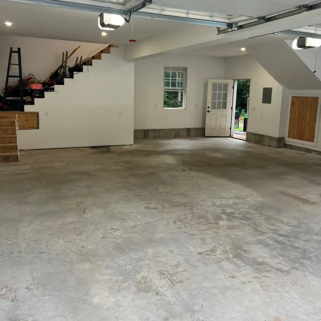 Garage with concrete floor, white walls, and an open door leading outside.