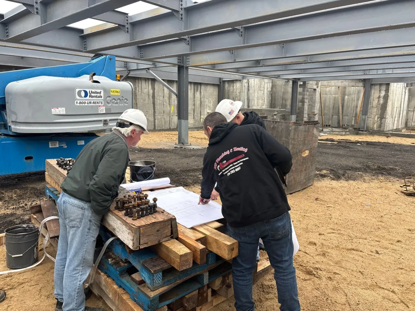 a group of men are looking at a blueprint on a construction site