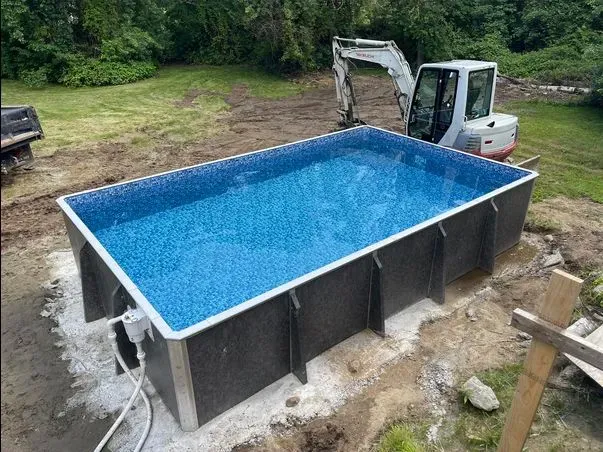 A swimming pool is being built in a backyard with a bulldozer in the background.
