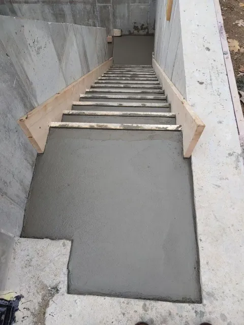 A concrete staircase is being built in a basement.