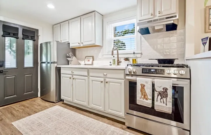 Modern kitchen, white cabinets, stainless appliances, wood floor, Home.