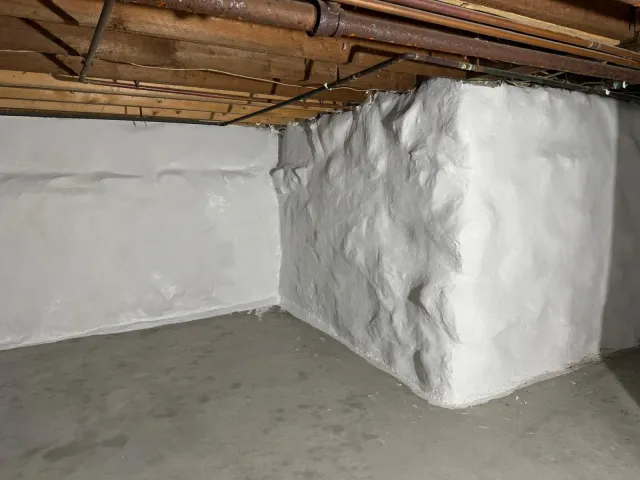 Whitewashed concrete basement walls, exposed beams, and pipes overhead.