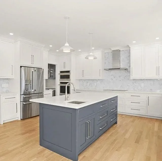 Modern kitchen with white cabinetry, a blue island, stainless steel appliances, and hardwood floors.