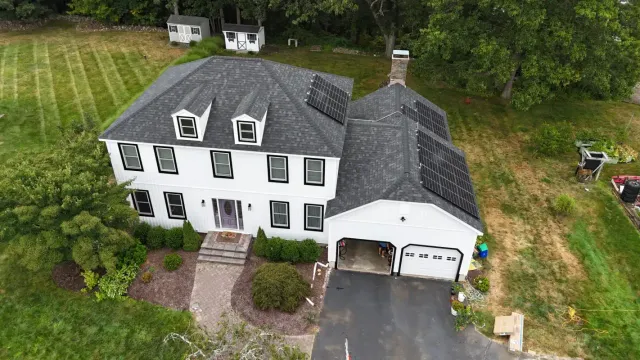 Aerial view of a white house with a new grey shingle roof
