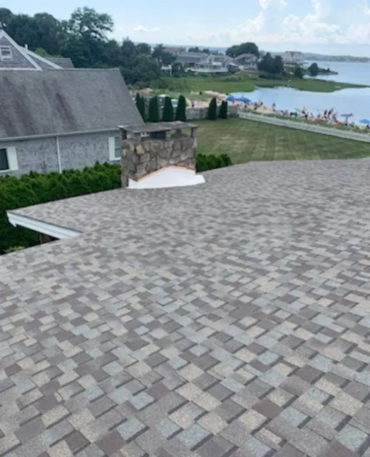 Stone patio overlooking a lake and landscaped hillside beside a house under a cloudy sky