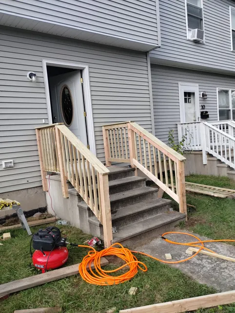 Newly built wooden porch steps with railing in front of a house.