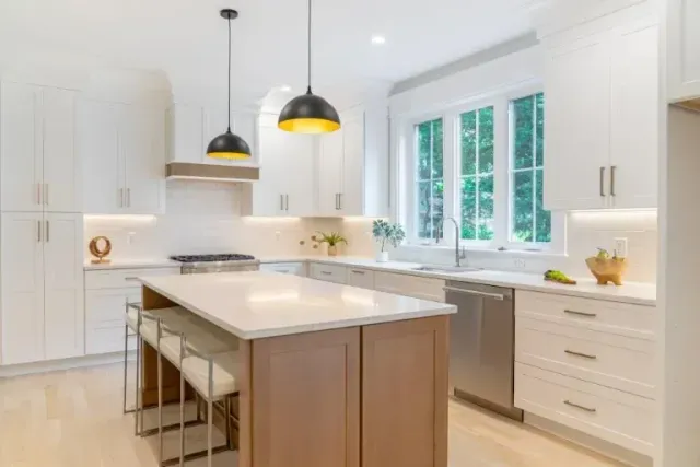 Bright white kitchen with island, pendant lights, and large window over the sink
