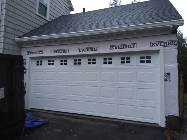 White double garage door on a house exterior with “EVERBILT” branding above it.