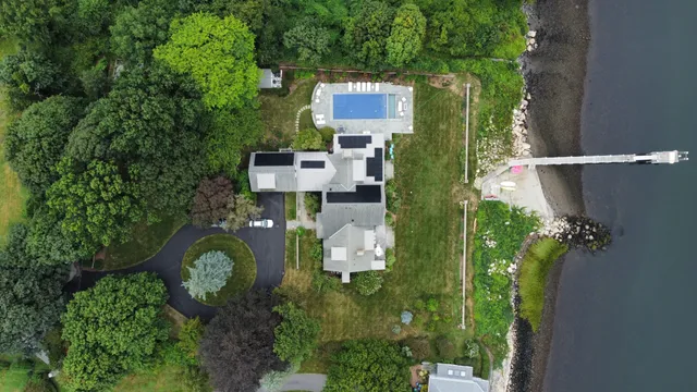 Aerial view of a large home on the water in Portsmouth, RI. This Sunwatt Solar installation includes several panels to help offset the cost of the running a heated pool and other electricity needs.