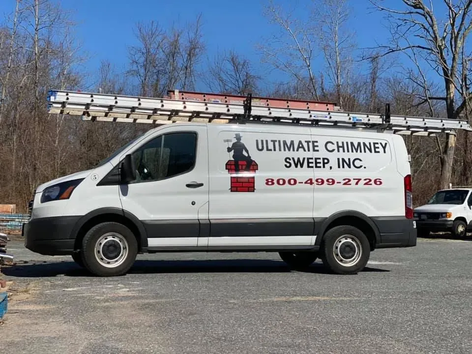 A white van with a ladder on top of it is parked in a parking lot.