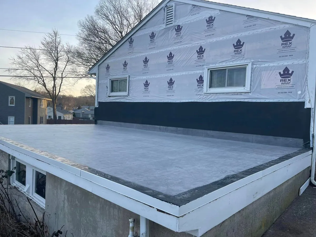 Newly installed rubber flat roof and house wrap on a home exterior tear off