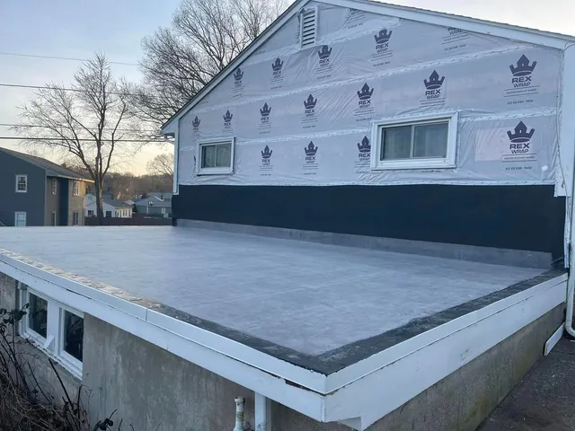 Newly installed rubber flat roof and house wrap on a home exterior tear off