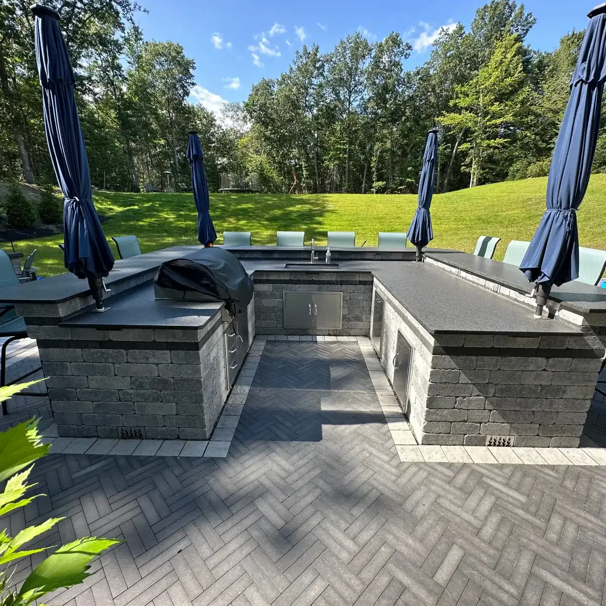 Outdoor kitchen with a black granite counter, sink and built-in grill