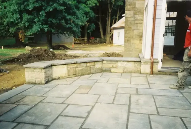 Bluestone patio with a low stone seat wall beside the house