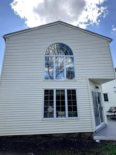 Bright clean cream siding on a two-story gable after soft wash
