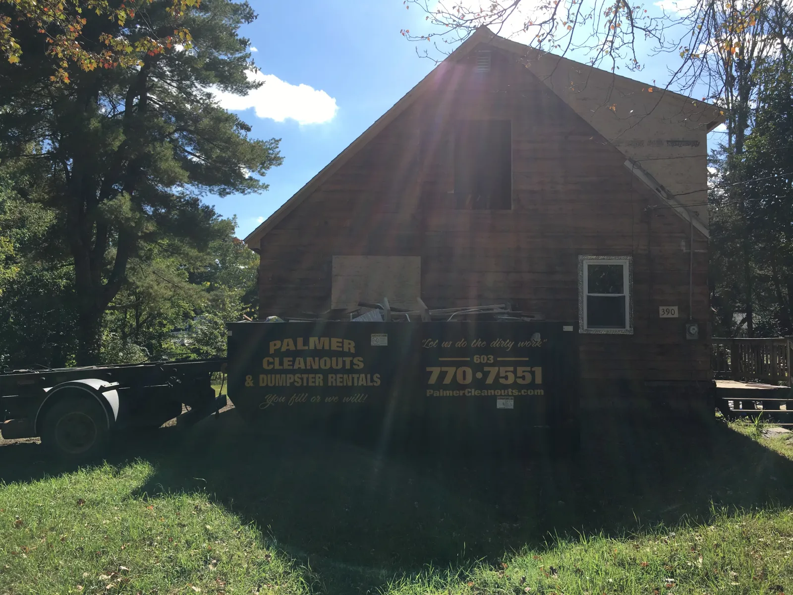 A dumpster from Palmer Cleanouts & Disposal, LLC parked in front of a house