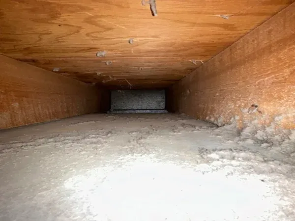 Air duct before cleaning - a heavy layer of dust and lint inside the duct