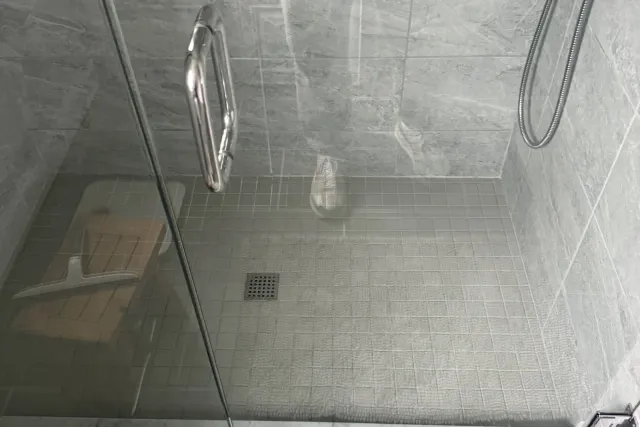 Before: existing glass shower with the original grey mosaic floor, photographed the day before tear-out — Newington, CT