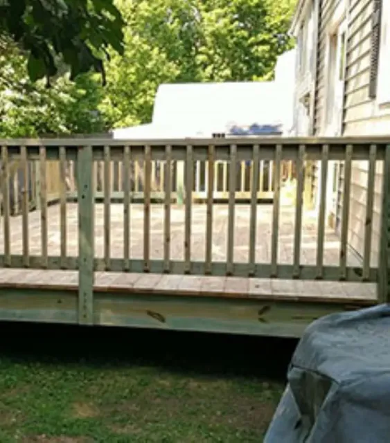 A wooden deck with a railing leading to a house.