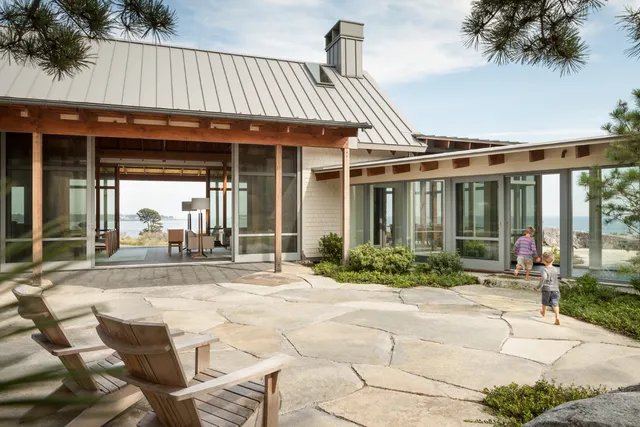 Coastal home with expansive glass doors and children playing, showcasing craftsmanship and open design.