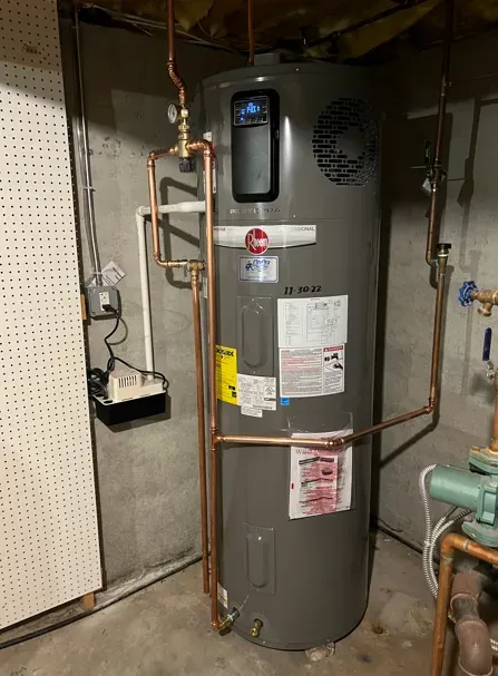 Water heater in a basement utility room with copper pipes and a pressure gauge.