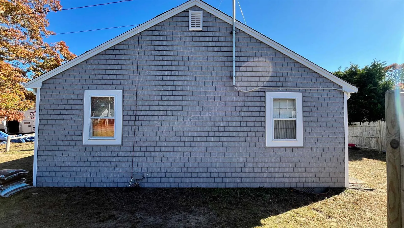 Home exterior with gray shake siding, white trim, and two windows
