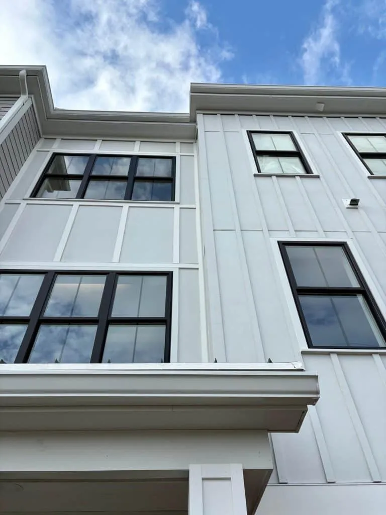 Modern building exterior featuring white paneling and large black-framed windows against a blue sky, representing Dartmouth Building Supply's expertise in architectural design for commercial and multifamily construction projects.