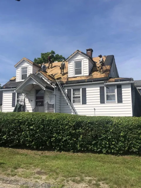 A white house is being remodeled with a roof being installed.