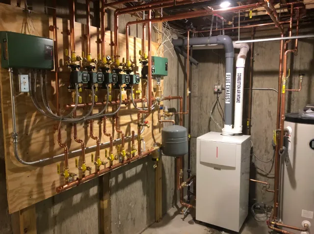 A room filled with lots of pipes and a boiler.