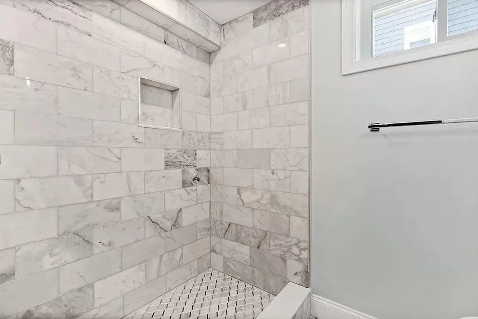 A bathroom with marble tiles and a walk in shower.