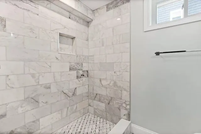 A bathroom with marble tiles and a walk in shower.
