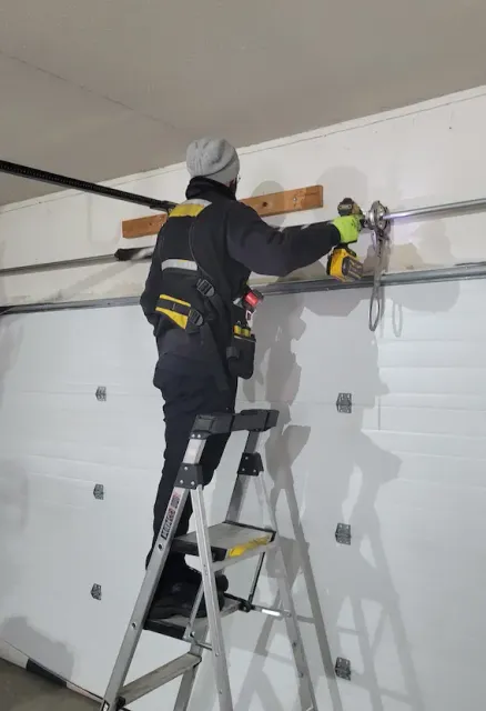 Professional garage door spring service: technician using a specialized torsion spring tensioning device for precise adjustment - Ariel Garage Door LLC, Waterbury CT.