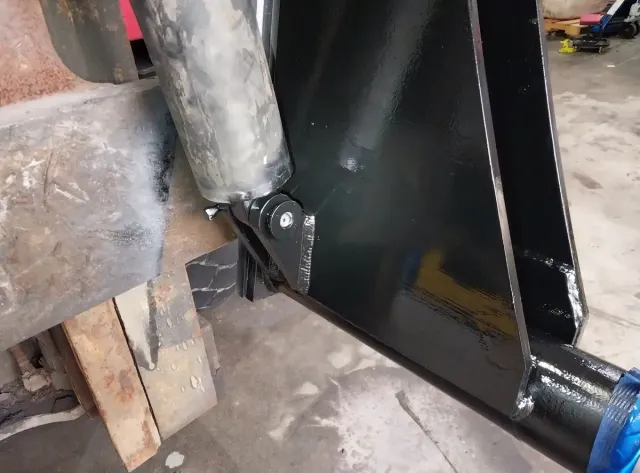 Blue-painted custom metal part with secure attachment loop, fabricated and coated by Warrior Welding for structural use