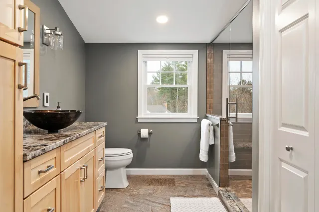 Hillside primary bathroom remodel in Southern New Hampshire — spa-style walk-in shower with frameless glass by Oak Hill Design & Build