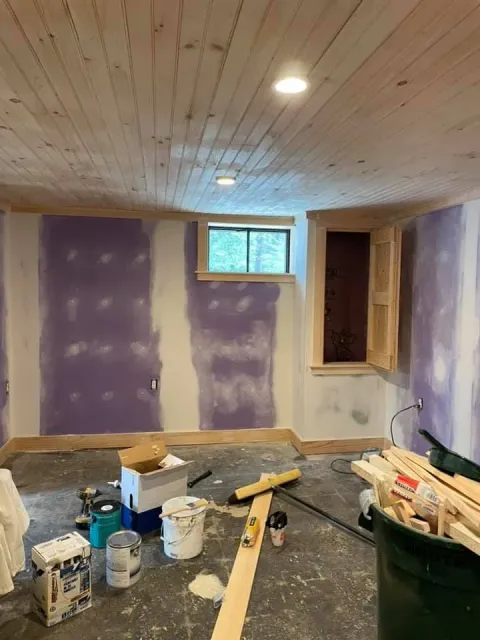 A room with purple walls and a window is being painted.
