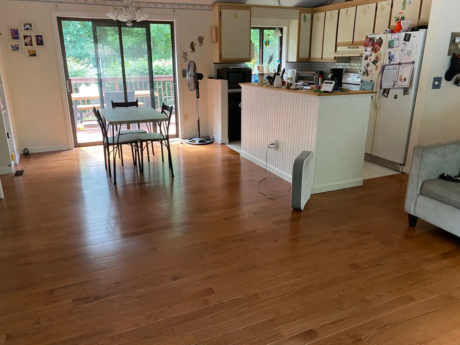 A living room with hardwood floors , a table and chairs , and a kitchen.