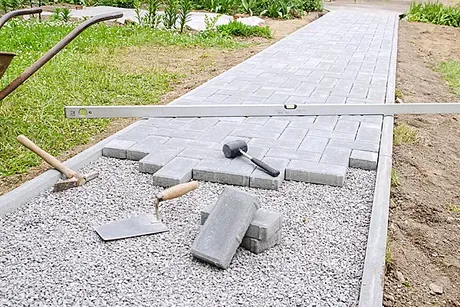 A walkway is being built with bricks and tools.