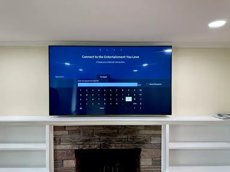 Wall-mounted TV displaying a blue calendar screen above a brick fireplace in a white room