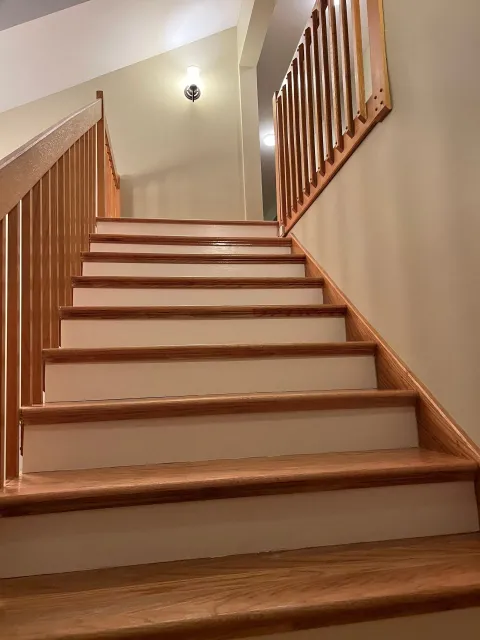 A wooden staircase with white steps and a wooden railing