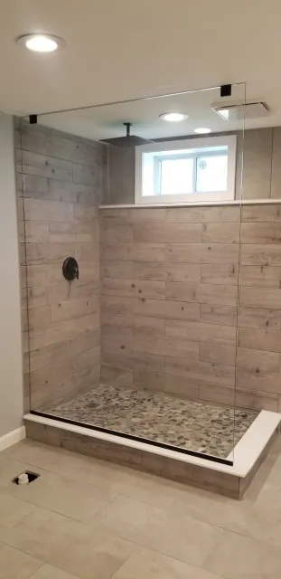 A bathroom with a walk in shower and a window.