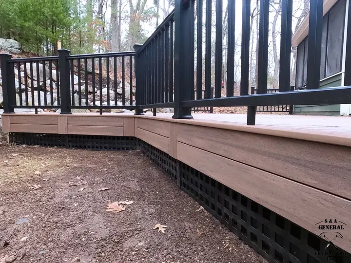 Brown and black deck with black railings and lattice skirting in an outdoor setting.