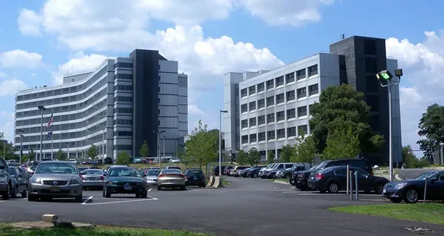 A lot of cars are parked in front of a large building