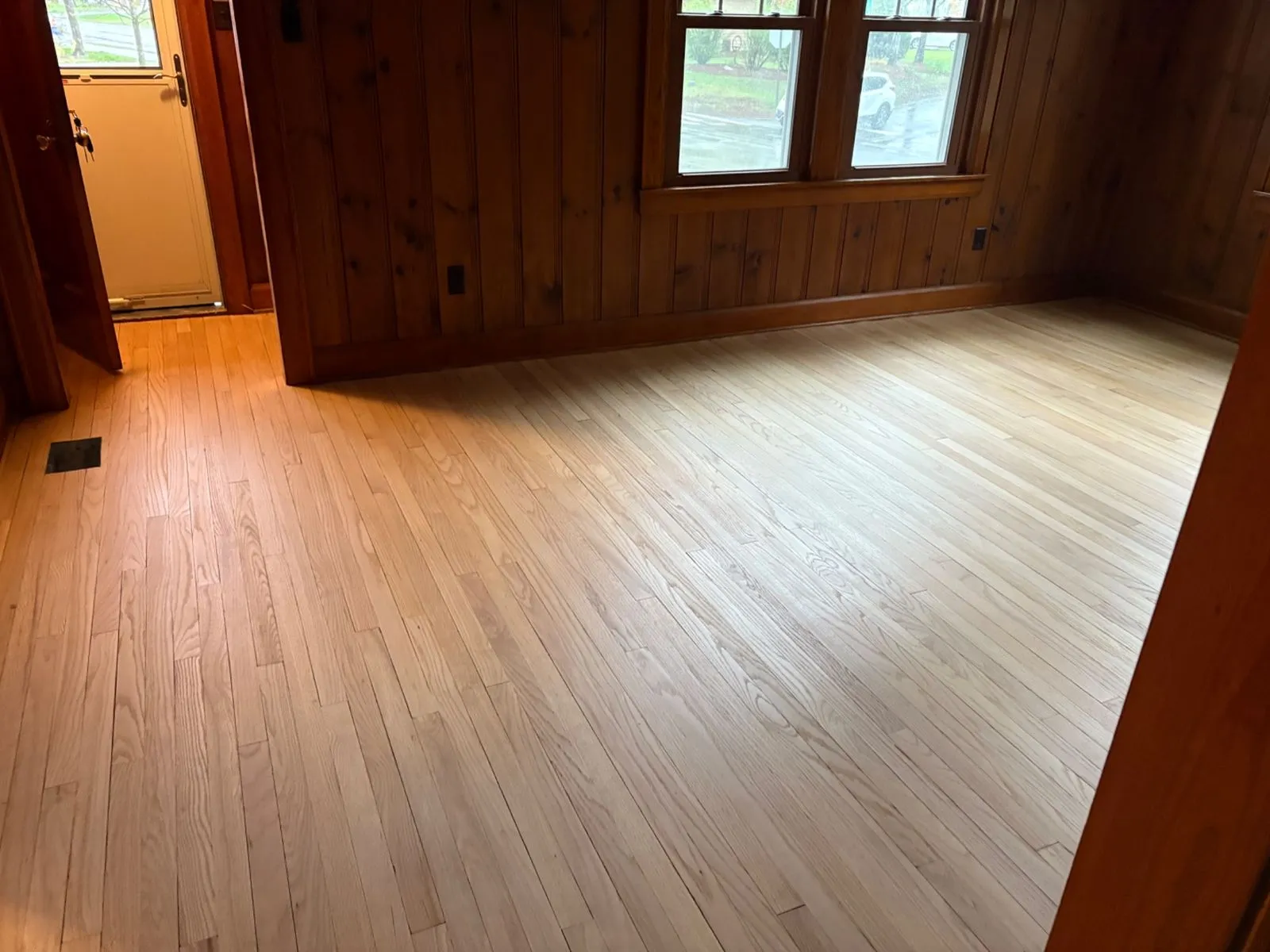 Refinished hardwood floor in a knotty-pine room