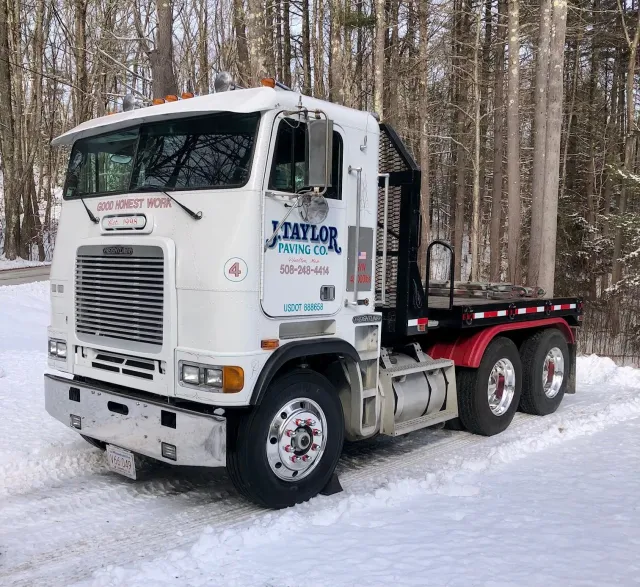 A white taylor truck is parked in the snow.