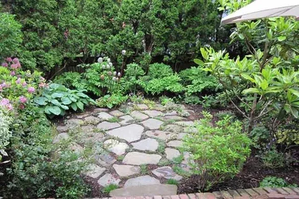 Irregular flagstone patio set into a shaded pocket garden