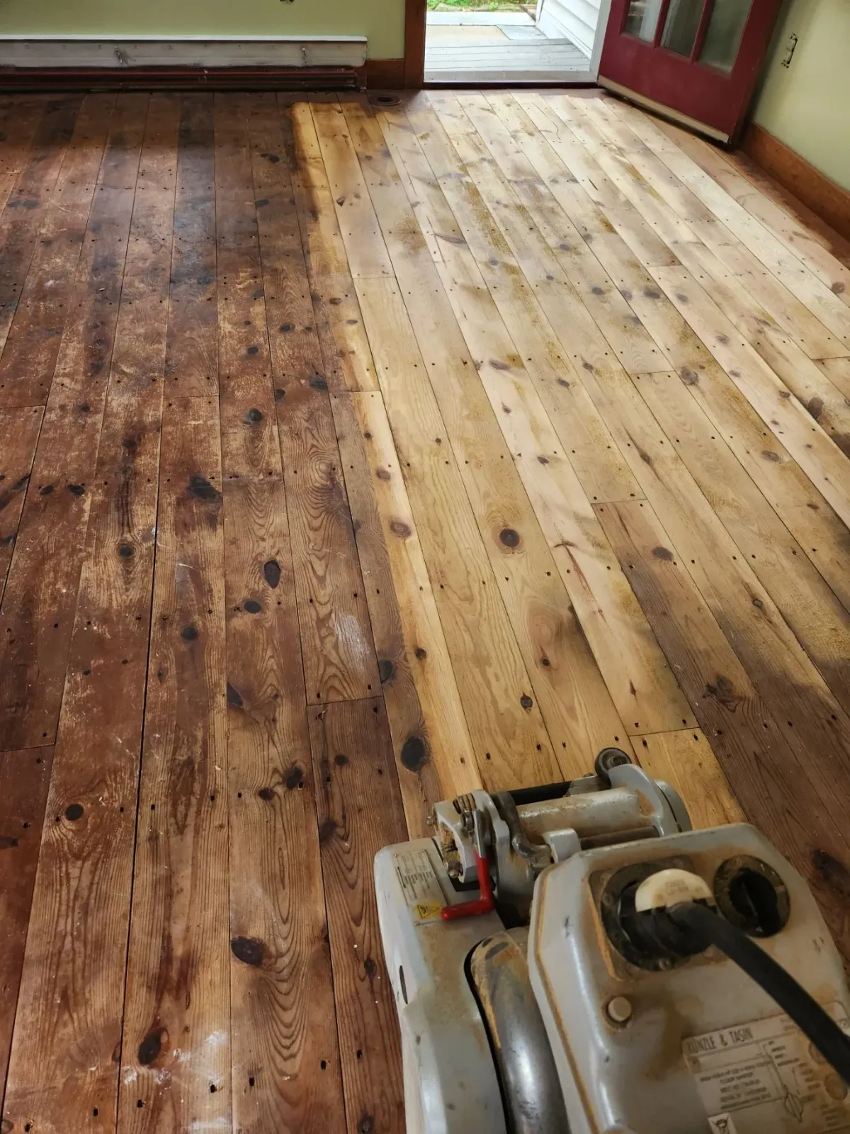 A machine is being used to sand a wooden floor